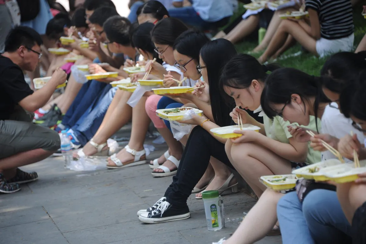 Postgraduate applicants sitting on ground have meals outside a assembly hall on July 29, 2015 in Jinan, Shandong Province of China. (VCG/VCG via Getty Images)