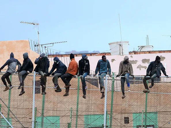Would-be immigrants sit atop a border fence separating Morocco from the north African Spanish enclave of Melilla on Feb.19, 2015. (Angela Rios/AFP/Getty Images)
