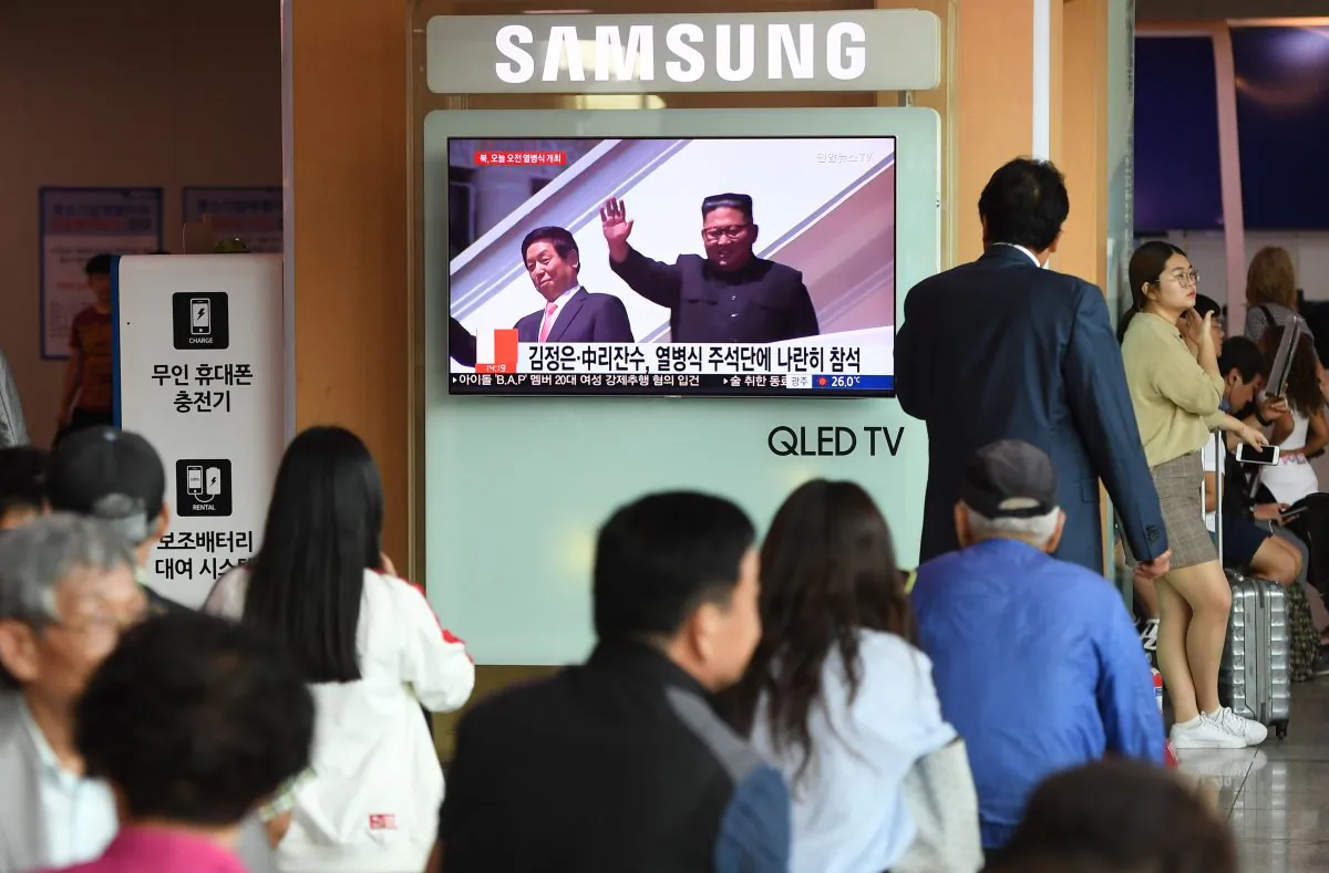 People watch a television news reporting a parade marking the 70th anniversary of the foundation of North Korea held in Pyongyang and showing North Korean leader Kim Jong-Un (R) and China's Chairman of the Standing Committee of the National People's Congress Li Zhanshu (L), at a railway station in Seoul on Sept. 9, 2018. (Jung Yeon-je/AFP/Getty Images)