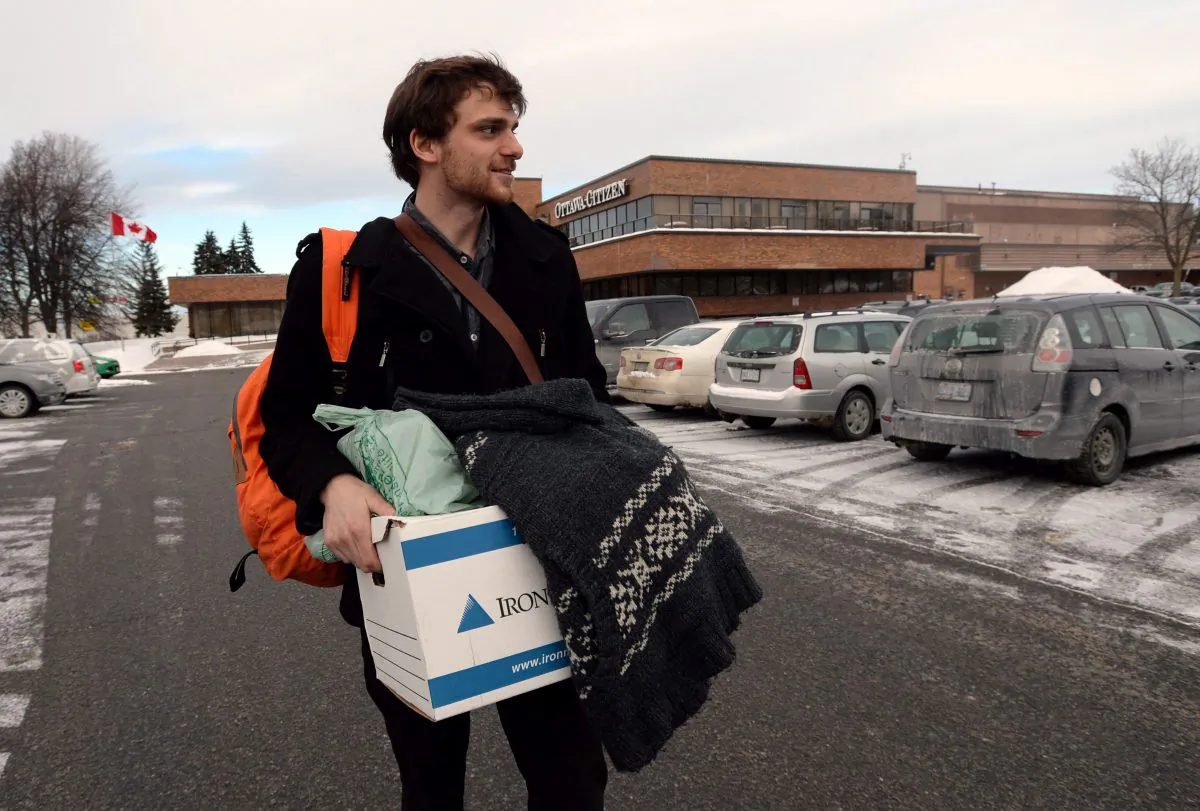 Multimedia reporter Sam Cooley makes his way to his car after being laid off from the Postmedia-owned Ottawa Sun on Jan. 19, 2016. Postmedia owns two newspapers in each of the cities of Ottawa, Calgary, Edmonton, and Vancouver. (The Canadian Press/Sean Kilpatrick)