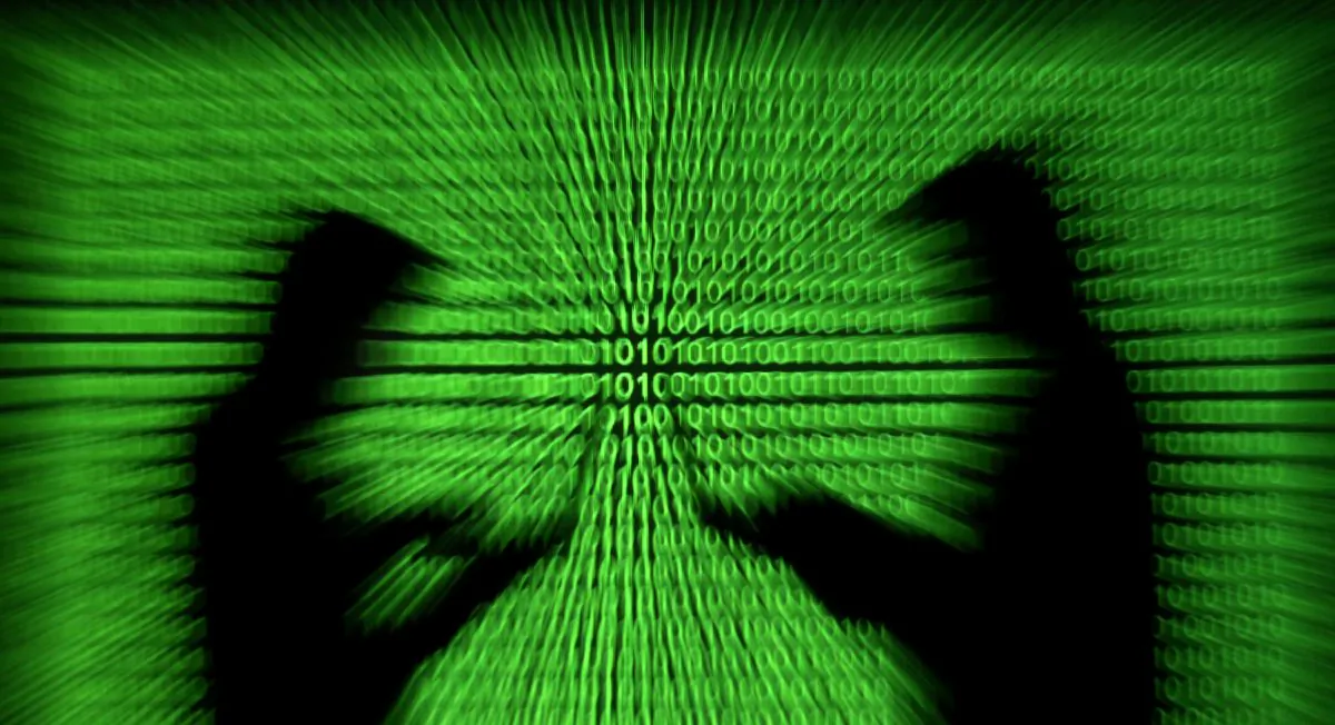 Silhouettes of laptop users next to a screen projection of binary code are seen in this picture illustration taken on March 28, 2018. (Dado Ruvic/Illustration/Reuters)