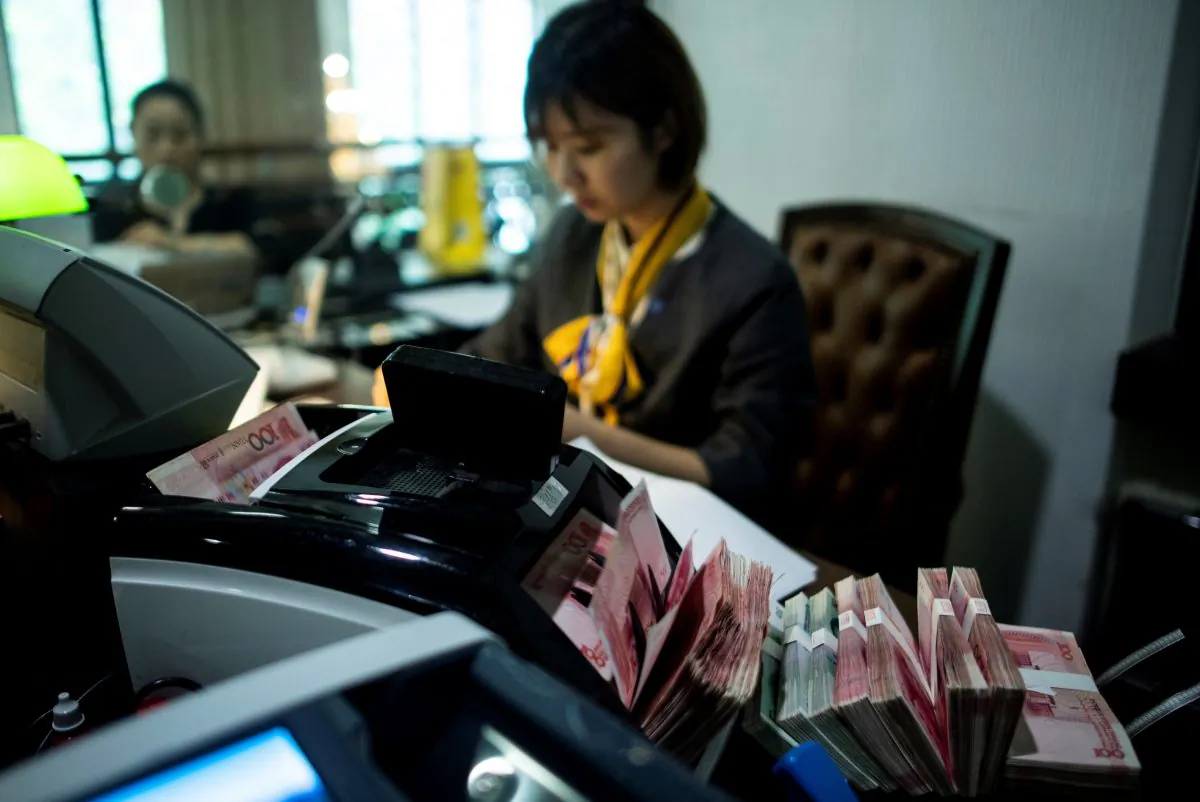 A bank employee uses a money counting machine to count out 100 yuan (14.6 USD) notes at a bank in Shanghai on August 8, 2018. - A rally in Asian markets stuttered on August 8, with early gains pared as the US-China trade row erodes investor confidence. But the yuan got some support after a news report said the Chinese central bank had emphasised the need for currency stability to the country's lenders as it looks to halt a slide in recent months. (Photo by Johannes EISELE / AFP) (Photo credit should read JOHANNES EISELE/AFP/Getty Images)