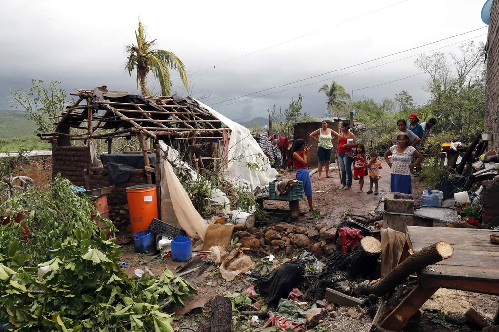 A family stands near their damaged home and debris in the aftermath of Hurricane Willa, in Escuinapa, Mexico, Oct. 24, 2018. (AP Photo/Marco Ugarte)