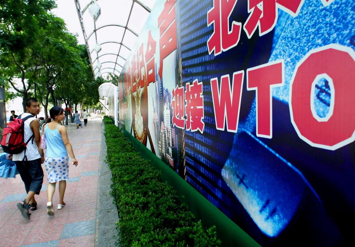 A young Chinese couple walk by a billboard promoting China's membership to the World Trade Organization (WTO), along a street in Beijing.