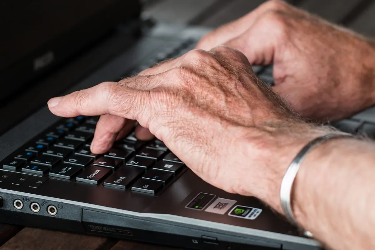 Old hands typing on laptop. (Pixabay)