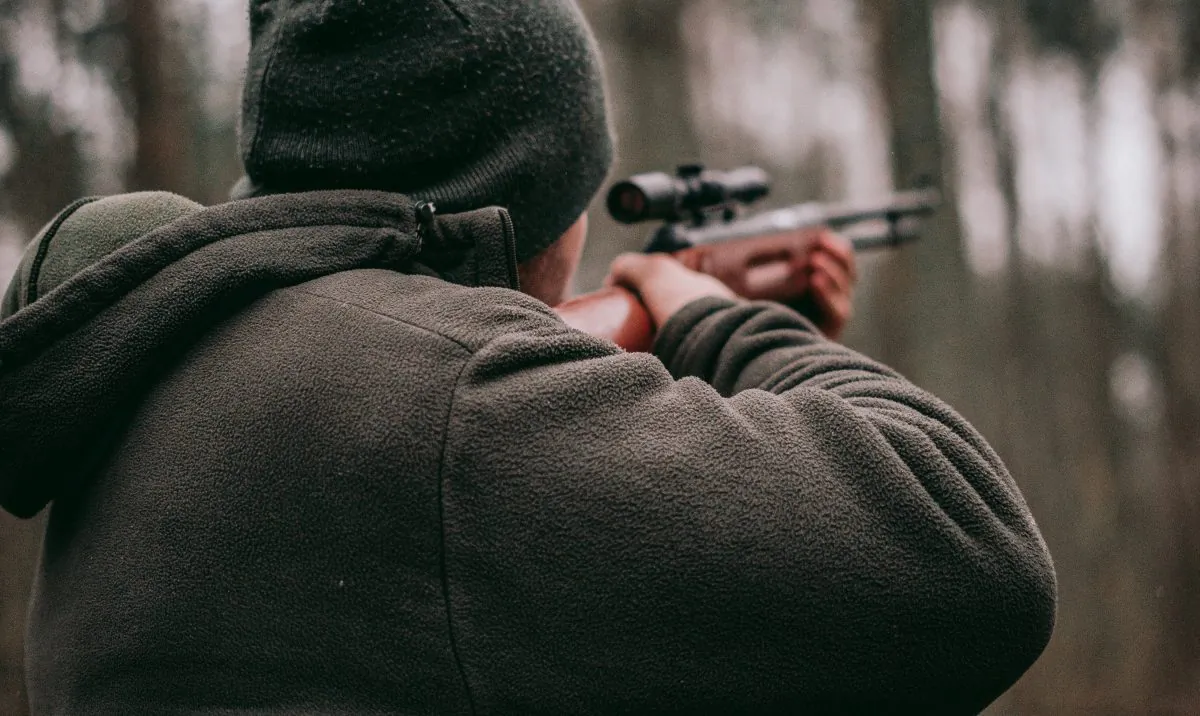 A hunter points a gun into the forest. (Sebastian Pociecha/Unsplash)