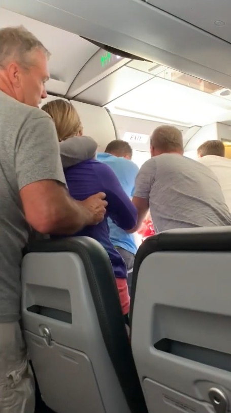 passengers and crew try to restrain man