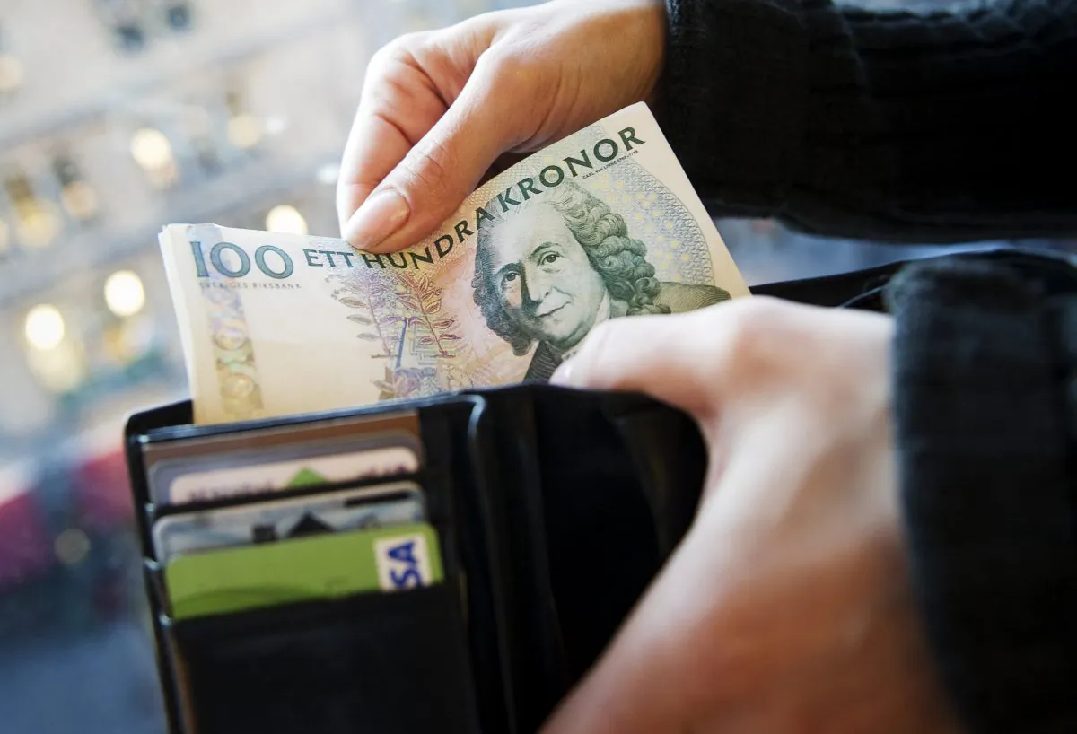 A women puts Swedish Crowns banknotes into her wallet in Stockholm in a file photo. (Jonathan Nackstrand/AFP/Getty Images)