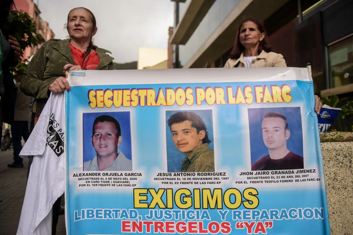 Women hold a banner with the portraits of three men kidnapped by the FARC guerrilla, during a protest outside at the Special Jurisdiction for Peace (JEP) headquarters in Bogota on July 13, 2018. (Raul Arboleda/AFP/Getty Images)