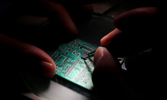 A researcher plants a semiconductor chip on an interface board, at the Tsinghua Unigroup research center in Beijing on Feb. 29, 2016. (Kim Kyung-Hoon/Reuters)