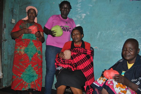 Cancer patients and survivors pose for a photo with knitted prosthetic breasts.