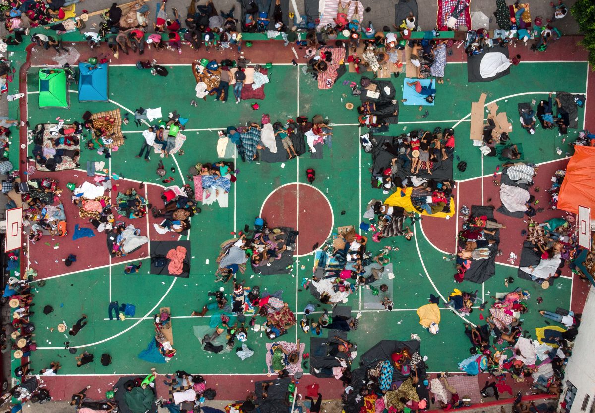 People in migrant caravan Rest on basketball court