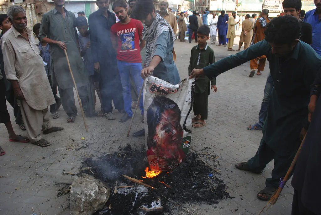 Pakistani protesters burn a poster image of Christian woman Asia Bibi, who has spent eight-years on death row accused of blasphemy and acquitted by a Supreme Court, in Hyderabad, Pakistan, Nov. 1, 2018. (AP Photo/Pervez Masih