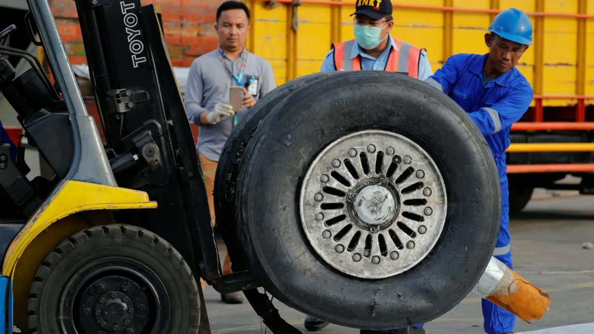 A worker assists his colleague as a tyre from Lion Air flight JT610 is lifted up at Tanjung Priok port in Jakarta, Indonesia, on Nov. 4, 2018. (Beawiharta/Reuters)