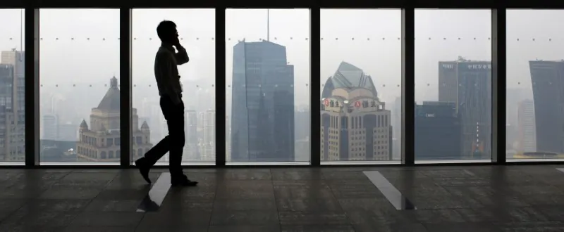 A man talks on a mobile phone as he walks past the view of the Shanghai skyline in China on Sept. 4, 2014. (Carlos Barria/Reuters)