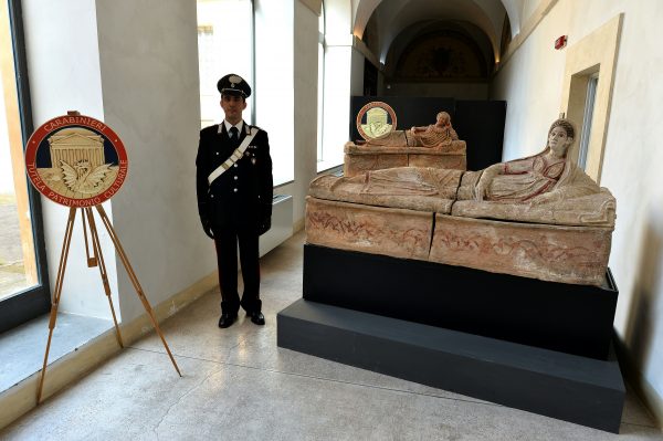 A carabiniere stands next to recovered archaeological artifacts