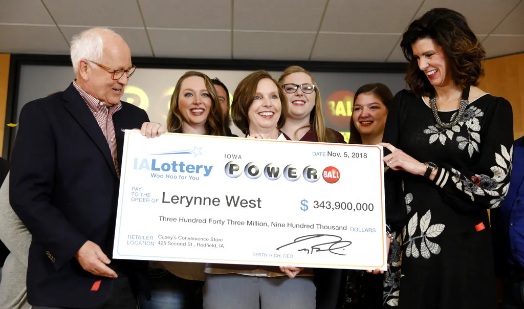 Iowa Lottery CEO Terry Rich, left, presents a check to Lerynne West, of Redfield, Iowa, center, for her share of a nearly $700 million Powerball prize, Mon., Nov. 5, 2018, at the Iowa Lottery headquarters in Clive, Iowa. (AP Photo/Charlie Neibergall)