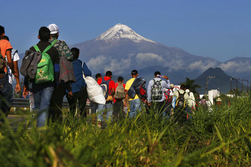 Central American migrants begin their morning trek as part of a caravan of some 4,000 people hoping to reach the United States border, as they face the Pico de Orizaba volcano upon departure from Cordoba, Veracruz state, Mexico, on Nov. 5, 2018. They reached Mexico City by Nov. 6. (AP Photo/Marco Ugarte)
