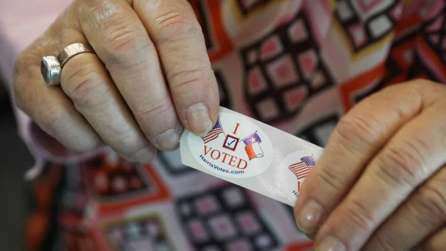 A woman in Texas hands out "I Voted" stickers to voters at the Rummel Creek Elementary School polling place in Houston on Nov. 6, 2018. (Loren Elliott/Getty Images)