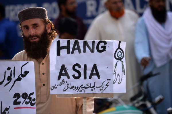 A supporter of Tehreek-e-Labaik, a hardline religious political party, holds a placard reading "Hang Asia"