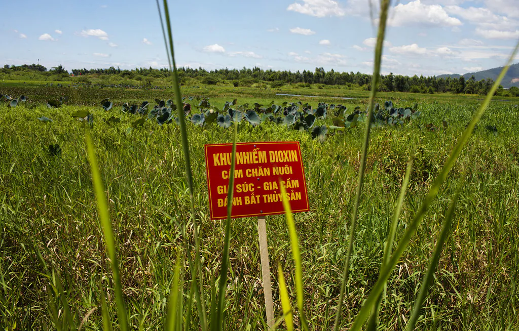 A warning sign stands in a field contaminated with dioxin near Danang airport, during a ceremony marking the start of a project to clean up dioxin left over from the Vietnam War, at a former U.S. military base in Danang, Vietnam. The sign reads; "Dioxin contamination zone - livestock, poultry and fishery operations not permitted." (Maika Elan/AP Photo)