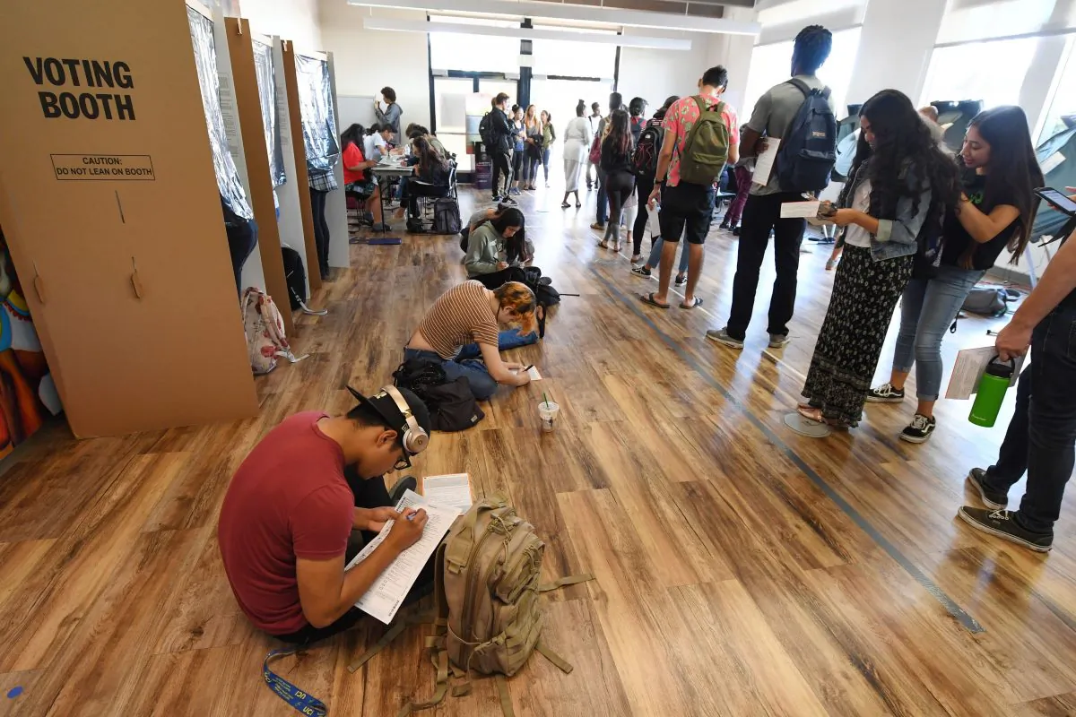 Students sitting on the floor of a polling station on the campus of the University of California, Irvine fill out provisional ballots as others wait in line to vote in Irvine, Calif. on Nov. 6, 2018. (ROBYN BECK/AFP/Getty Images)