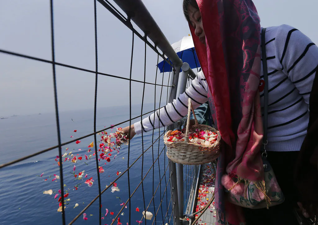 A relative sprinkles flowers for victims in the crashed Lion Air flight 610 aboard an Indonesia Navy ship in the waters where the airplane is believed to have crashed in Tanjung Karawang, Indonesia,Nov. 6, 2018. (AP/Tatan Syuflana)