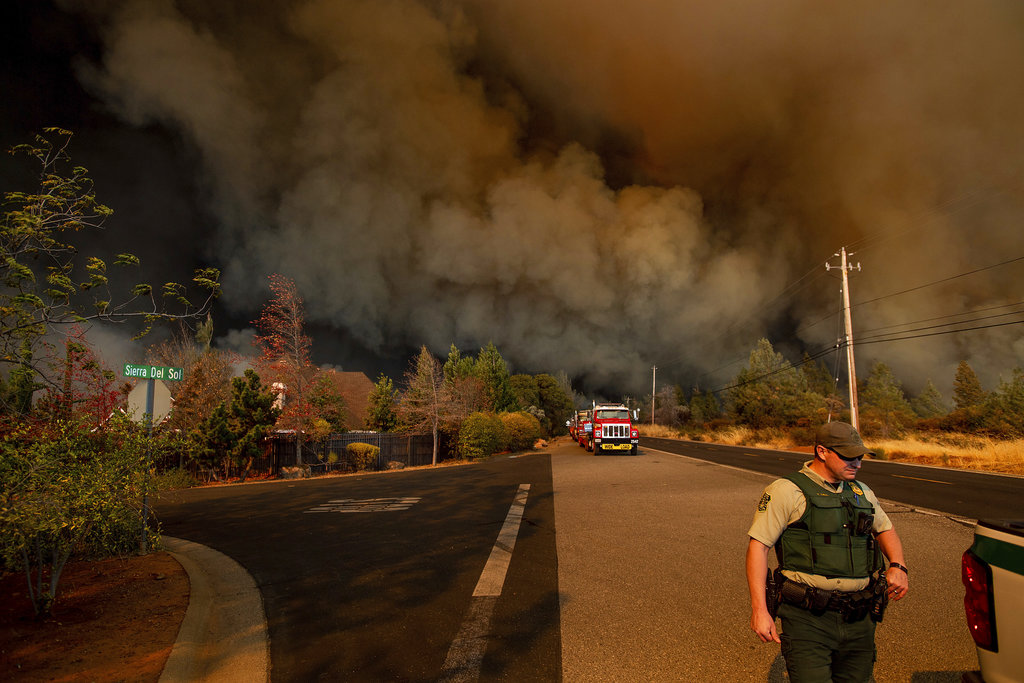 Police officer walking while large clouds of smoke are in the background