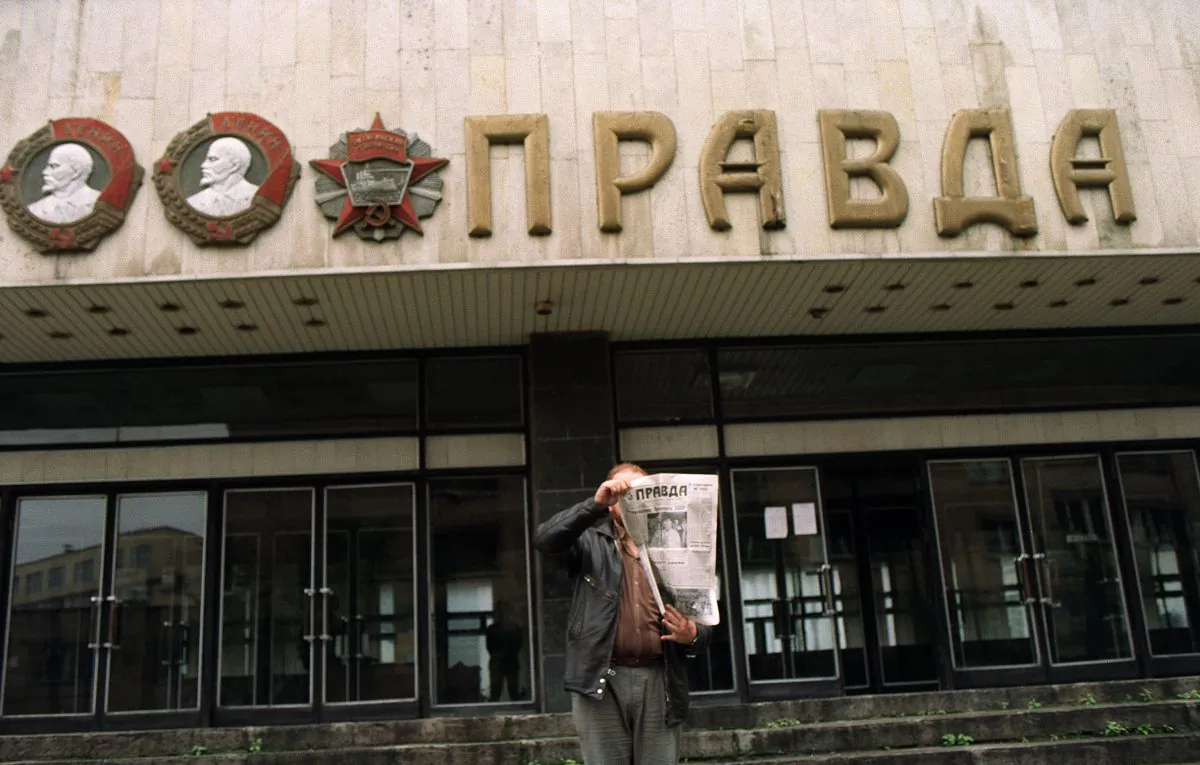 File photo of a man holding up a copy of "Pravda" in front of the entrance of the building of the Soviet newspaper in Moscow on Aug. 28, 1991. (GERARD FOUET/AFP/Getty Images)