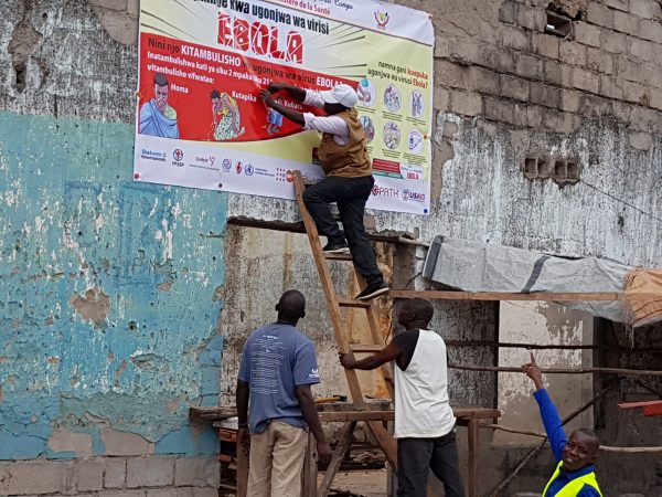Workers fix Ebola awareness poster