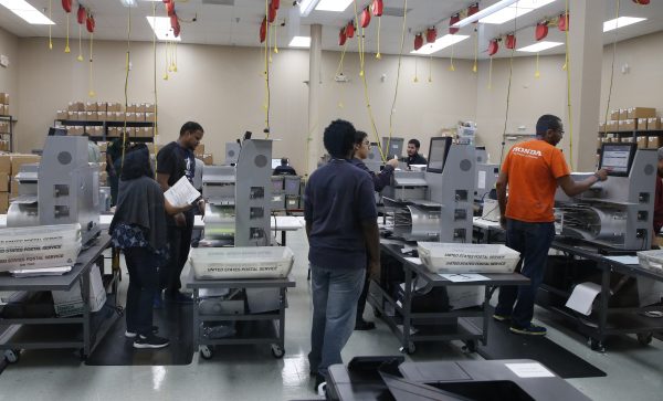 Elections workers feed ballots into tabulation machines at the Broward County Supervisor of Elections office in Lauderhill