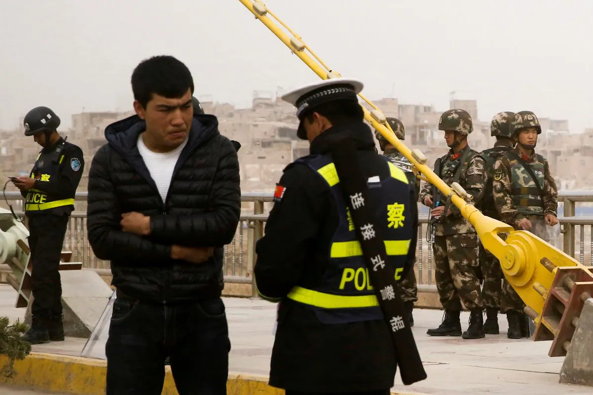 A police officer checks the identity card of a man as security forces keep watch in a street in Kashgar, Xinjiang region, China on March 24, 2017. (Thomas Peter/Reuters)