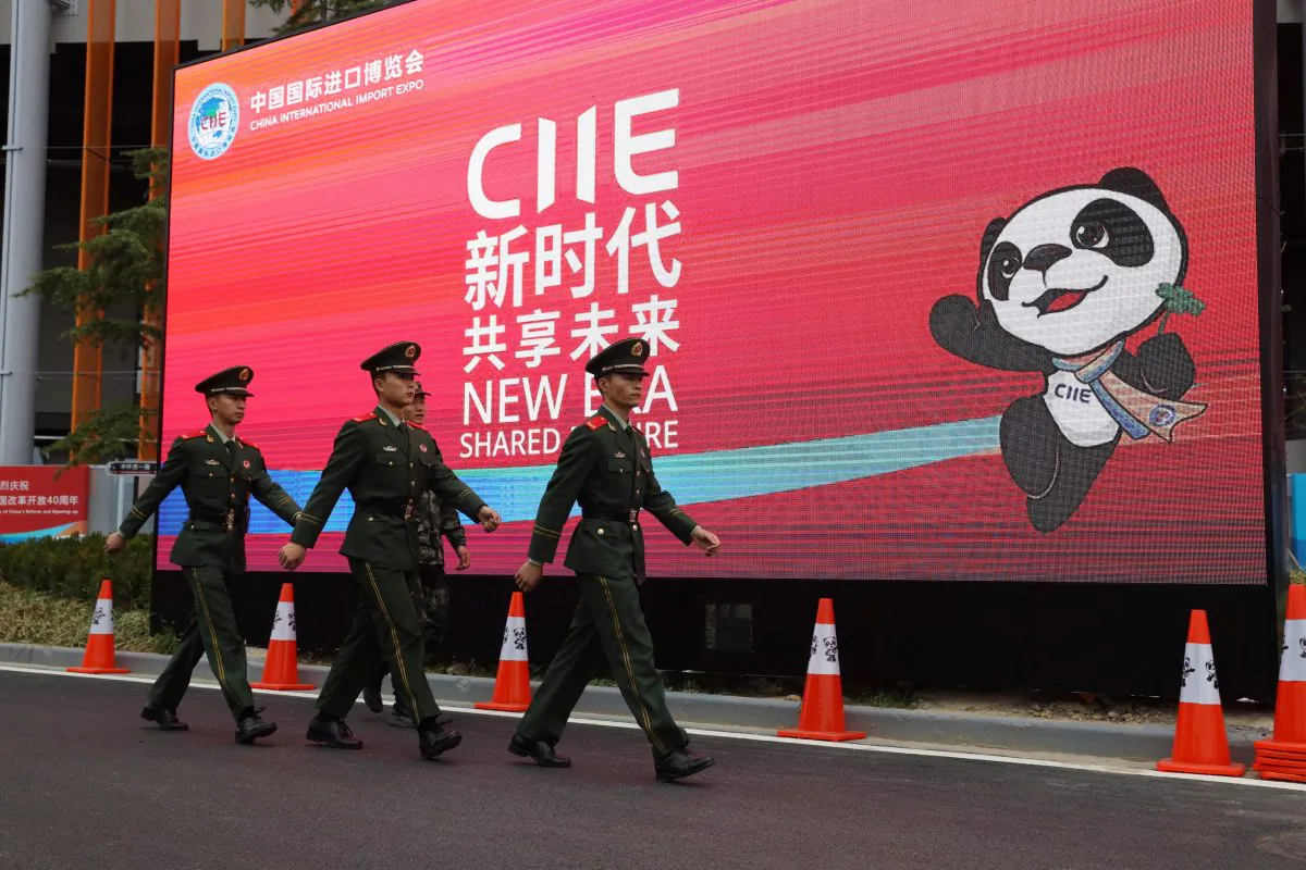 Chinese paramilitary policemen march near a billboard for the China International Import Expo in Shanghai on Nov. 4. Visitors to the vast trade fair, meant to rebrand China as a welcoming import market, could sip Moroccan wine, ogle Italian yachts, and watch a Japanese industrial robot play Ping-Pong. (AP Photo/Ng Han Guan)