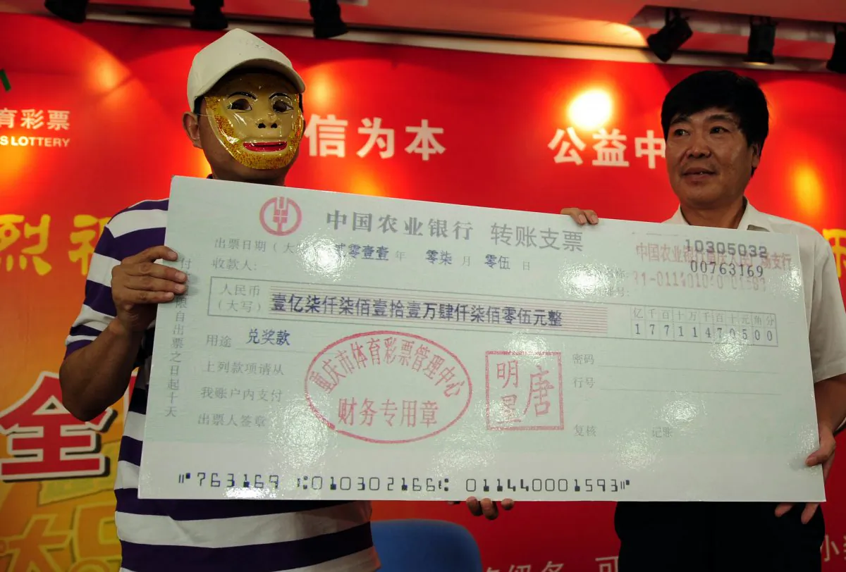 A Chinese man wears a mask to hide his identity as he recieves a mock check for 177 million yuan (26 million USD) after winning the jackpot in the China Sport lottery in Chongqing on July 5, 2011. (STR/AFP/Getty Images)