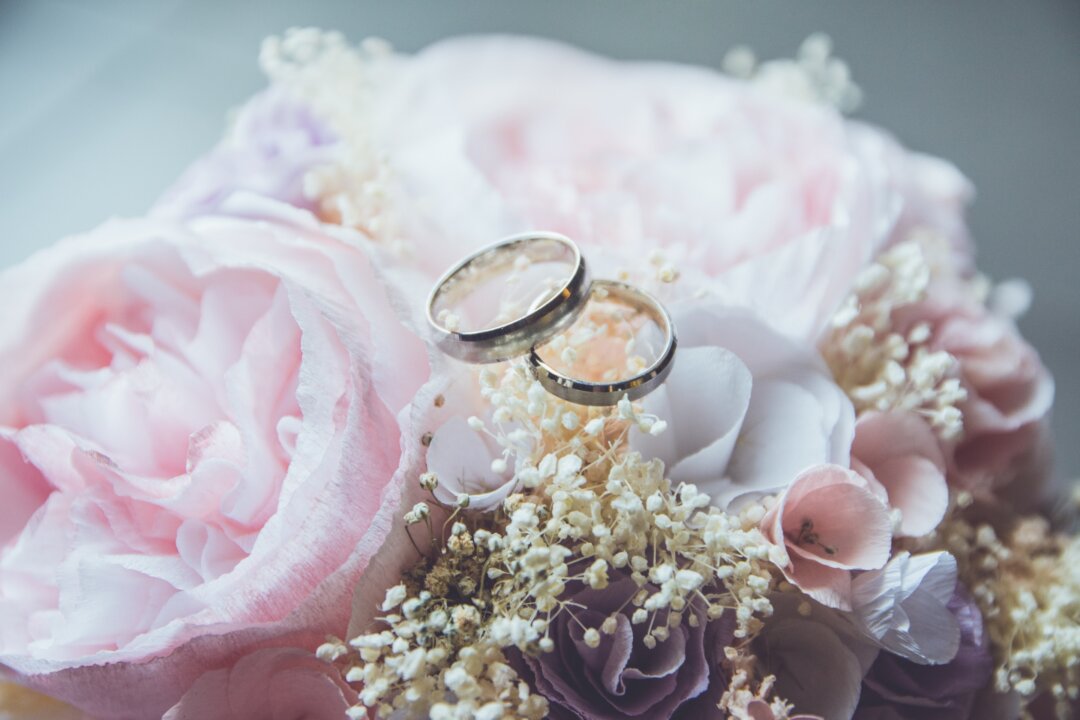 Two rings sit on a floral bouquet. (Beatriz Perez-Moya/Unsplash)