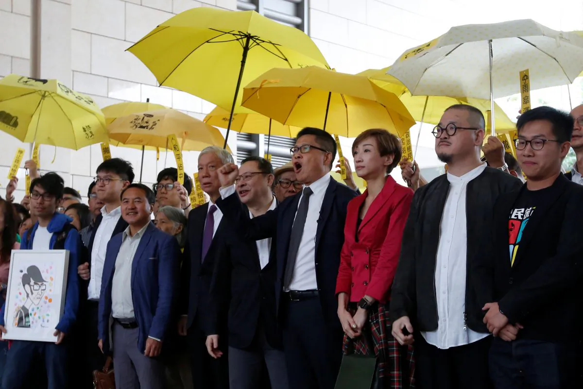 (L-R) Pro-democracy activists Chung Yiu-wa, Cheung Sau-yin, Lee Wing-tat, Chu Yiu-ming, Benny Tai, Chan Kin-man, Tanya Chan, Shiu Ka-chun and Raphael Wong pose outside a court in Hong Kong on Nov. 19, 2018. (Bobby Yip/Reuters)