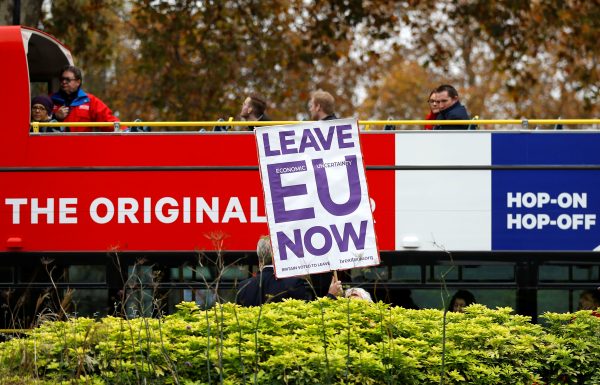 A pro-Brexit campaigner holds a placard as a tourist bus passes by
