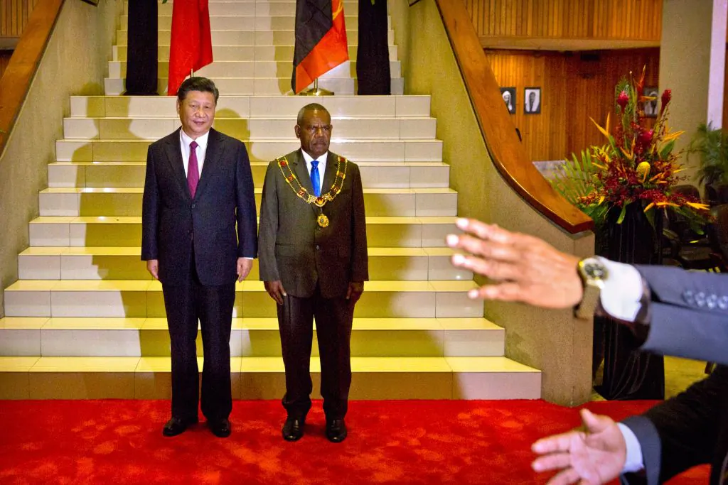 An official gestures as China's President Xi Jinping (L) and Papua New Guinea's Governor General Bob Dadae pose for photos before a meeting at Parliament House in Port Moresby on Nov. 16, 2018, ahead of the Asia-Pacific Economic Cooperation (APEC) Summit. (Mark Schiefelbein/AFP/Getty Images)
