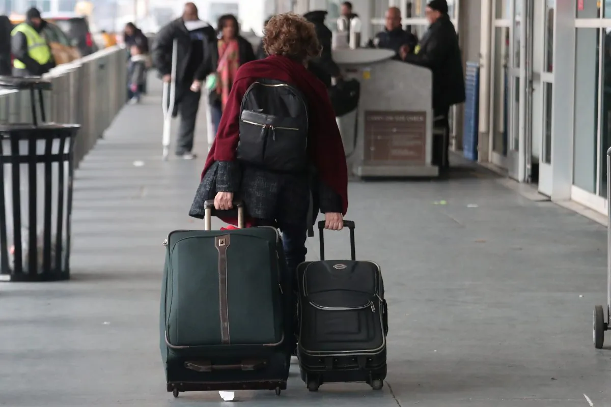 A woman carries her luggage to departing flights entrance at LaGuardia Airport in New York, on Nov. 20, 2018. (Shannon Stapleton/Reuters)