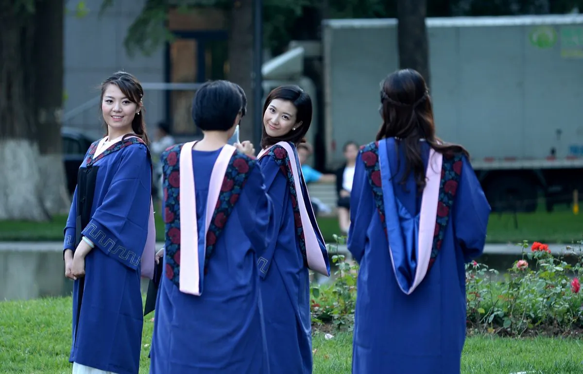 A group of students pose for photographs at a university in Beijing on June 8, 2015. Despite a boom in student numbers in recent years, many graduates from second and third-tier institutions face considerable employment uncertainty in an economy largely fuelled by a blue-collar workforce.    AFP PHOTO / WANG ZHAO        (Photo credit should read WANG ZHAO/AFP/Getty Images)