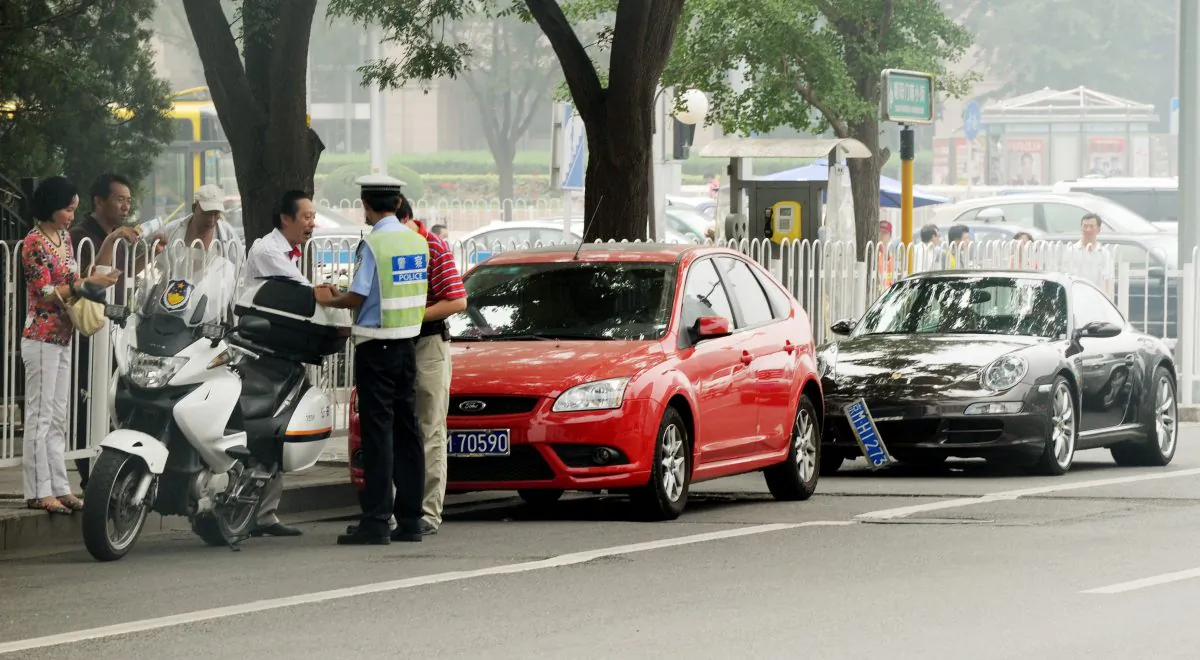 A Chinese policeman tries to resolve a traffic dispute between the driver of a luxury Porsche car and another after an accident in Beijing on Aug. 9, 2011. (Mark Ralston/AFP/Getty Images)