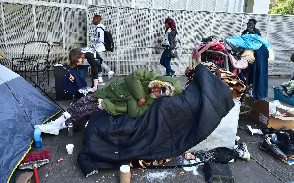 Homeless woman Caroline Francis places a platter of food for her neighbor on the street near the Los Angeles Mission on Dec. 22, 2017 in Los Angeles, California. 
(Frederic Brown/AFP/Getty Images)