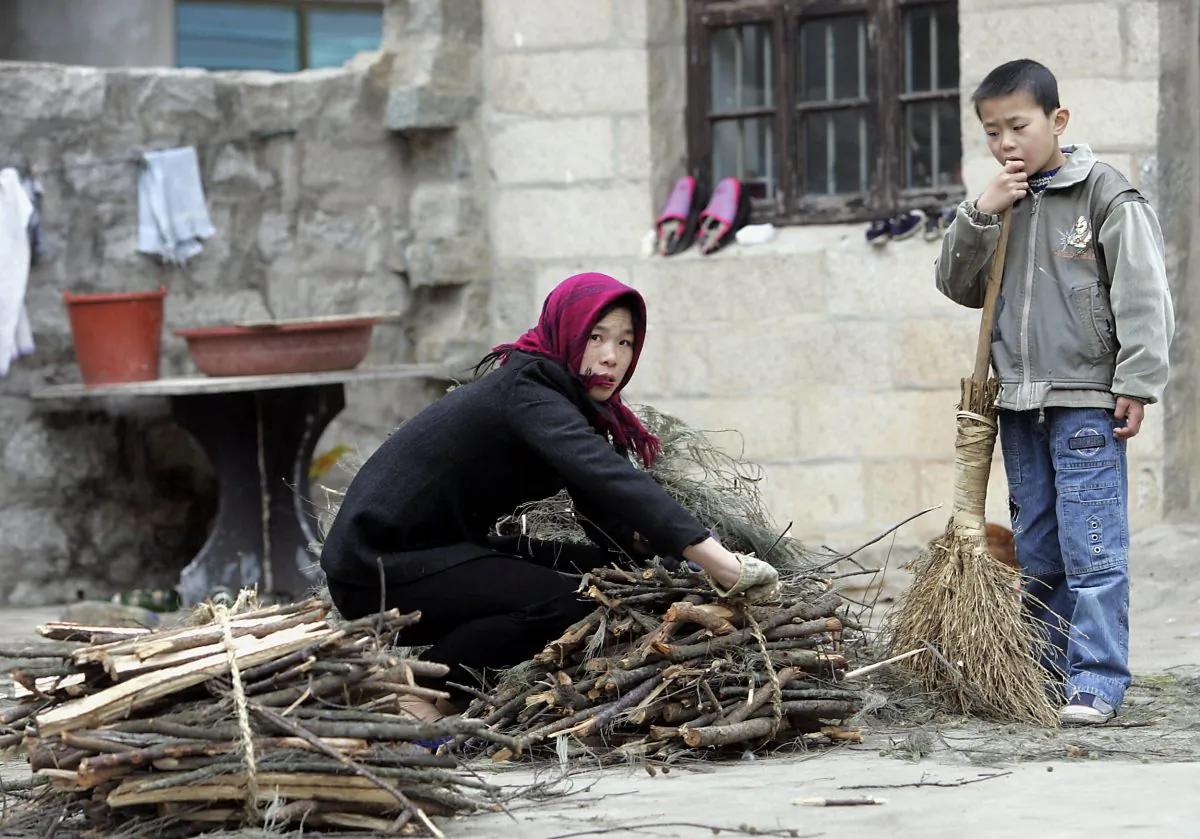 A woman farmer tieing a bunch of firewood as her son watches outside their home in Hutou village on Pingtan island. (GOH CHAI HIN/AFP/Getty Images)
