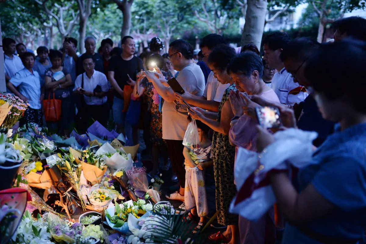 Children and adults pray during a candle-light vigil at the site of a knife attack which left two children dead in Shanghai, China on June 28, 2018. A man stabbed two boys to death outside a Shanghai elementary school on June 28, police said, one of the latest in a series of similar attacks in China in recent years. (AFP/Getty Images)
