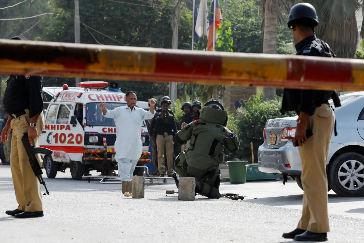 Police officers stand guard as a member of the bomb disposal unit (C) checks a bag with exlosives (unseen), after an attack on the Chinese consulate, in Karachi, Pakistan on Nov. 23, 2018. (Akhtar Soomro/Reuters)