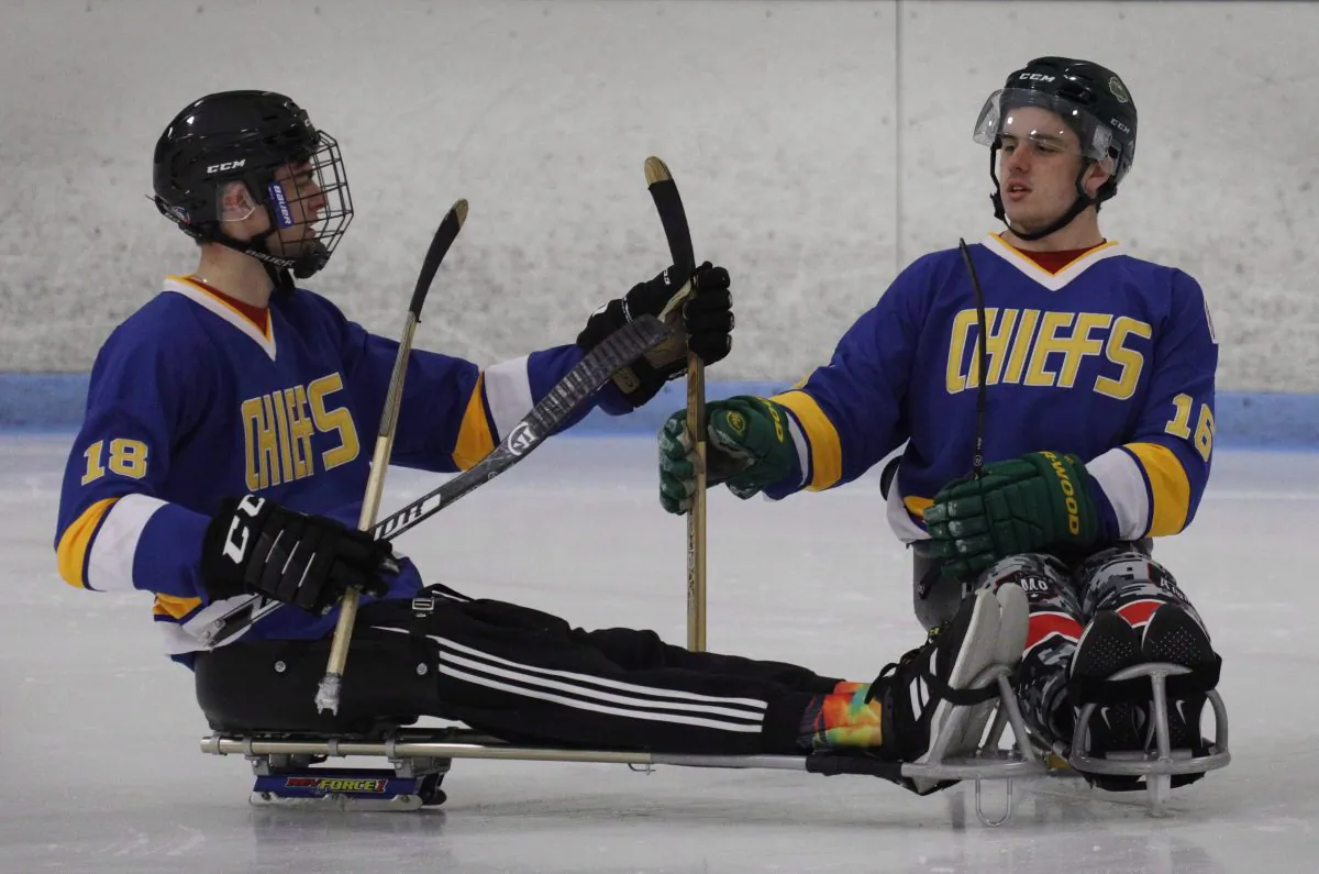 Humboldt Broncos hockey player Jacob Wassermann (L) and teammate Ryan Straschnitzki compare sticks during a sled hockey scrimmage at the Edge Ice Arena in Littleton, Colo., on Nov. 23, 2018. (The Canadian Press/Joe Mahoney)
