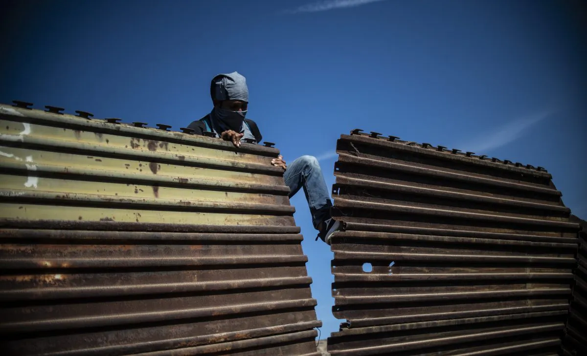 A Central American migrant tries to bring down part of the border fence between Mexico and the United States, near El Chaparral border crossing, in Tijuana, Baja California State, Mexico, on Nov 25, 2018. (Pedro Pardo/AFP/Getty Images)