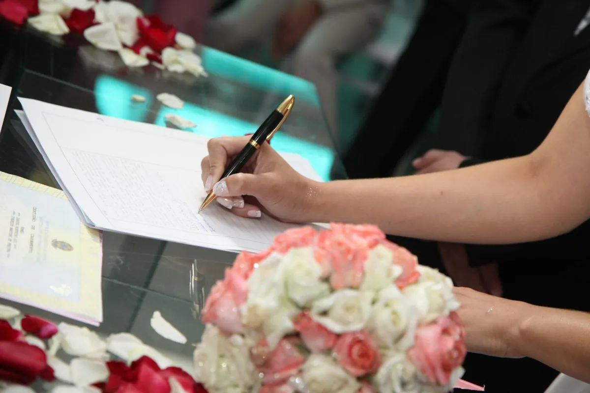 A bride's hand signs wedding documentation in this stock image. (Pixabay)