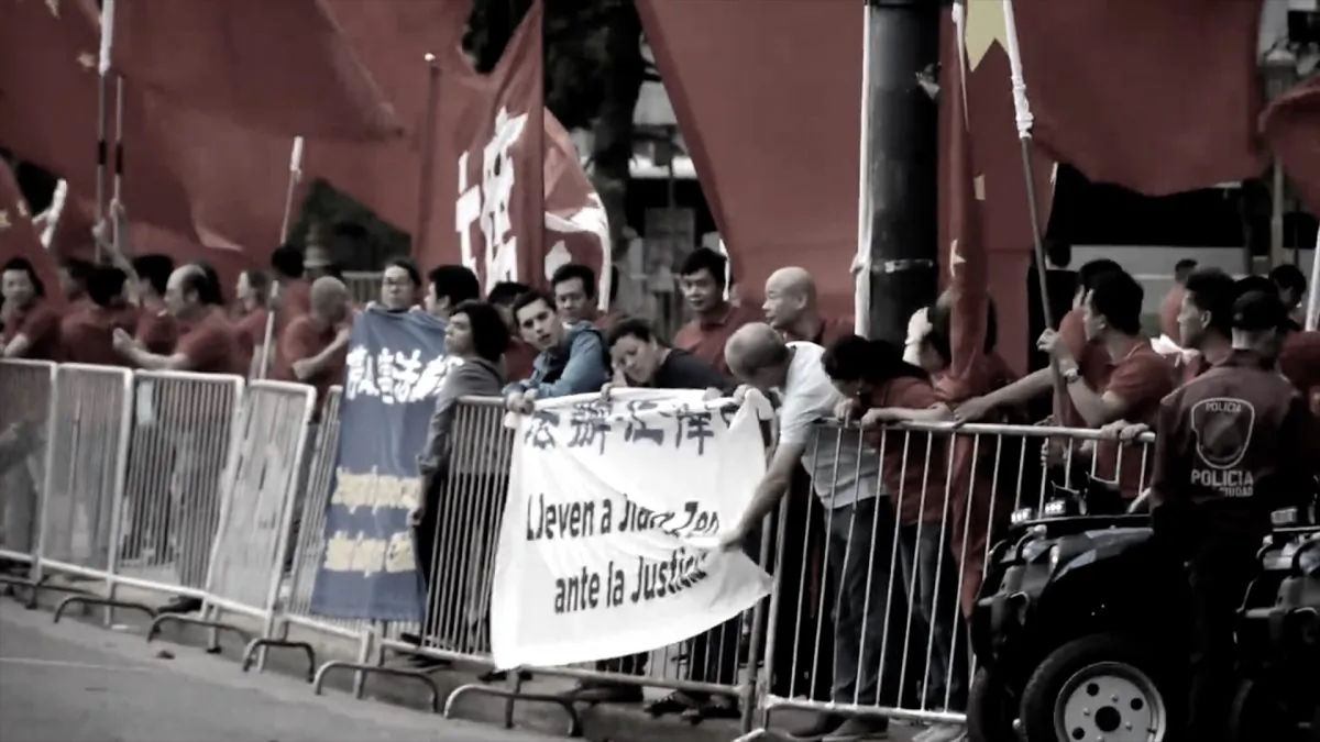 Nine Argentine Falun Gong practitioners hang two banners on the crowd control barriers, which say “Stop the persecution of Falun Gong” and “Bring Jiang Zemin to Justice” in Spanish and Chinese. The practitioners are surrounded by supporters of the Chinese Communist Party sent to welcome Chinese leader Xi Jinping. (Screenshot via YouTube)