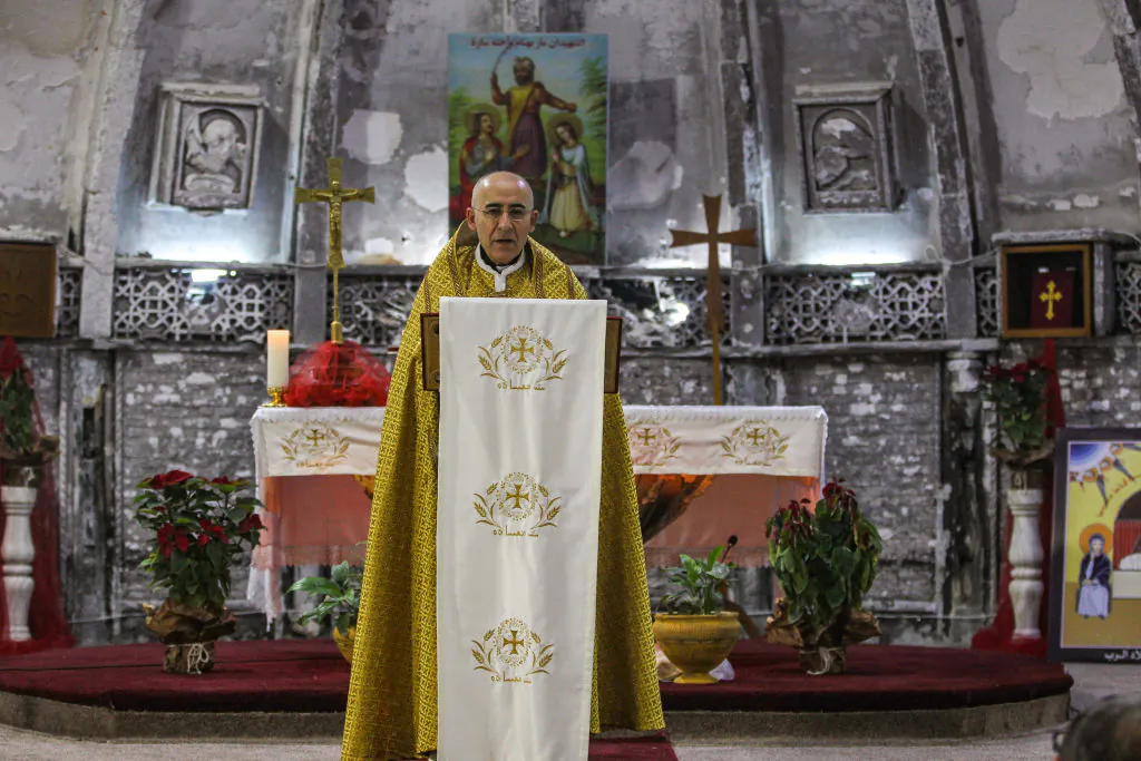 An Iraqi Syriac Catholic priest leads Christmas morning mass at the Mar Behnam and Mart Sarah Syriac Catholic Church, which was damaged and defaced during its occupation by Islamic State (IS) group fighters, in the predominantly Iraqi Christian town of Qaraqosh, in Niniveh province some 30 kilometres from Mosul, on Dec. 25, 2018. (Ahmad Al-Rubaye/AFP/Getty Images)